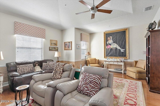 living room featuring ceiling fan, plenty of natural light, a textured ceiling, and light wood-type flooring