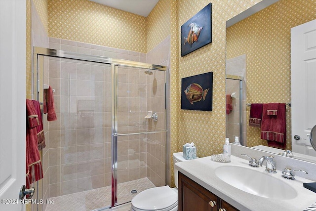 bathroom featuring vanity, toilet, and a shower with shower door