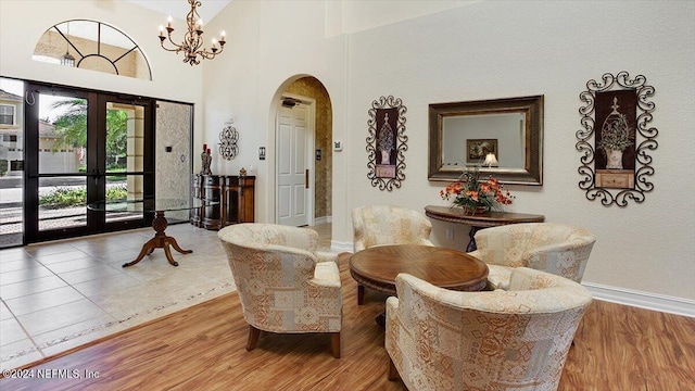 sitting room with a chandelier, french doors, wood-type flooring, and a high ceiling