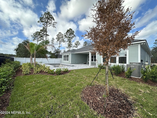 rear view of house featuring central AC unit, a patio area, and a yard