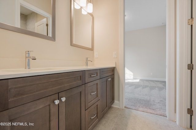 bathroom with baseboards, double vanity, a sink, and tile patterned floors