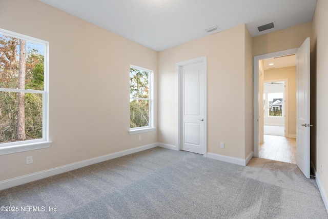 unfurnished bedroom with light colored carpet and multiple windows