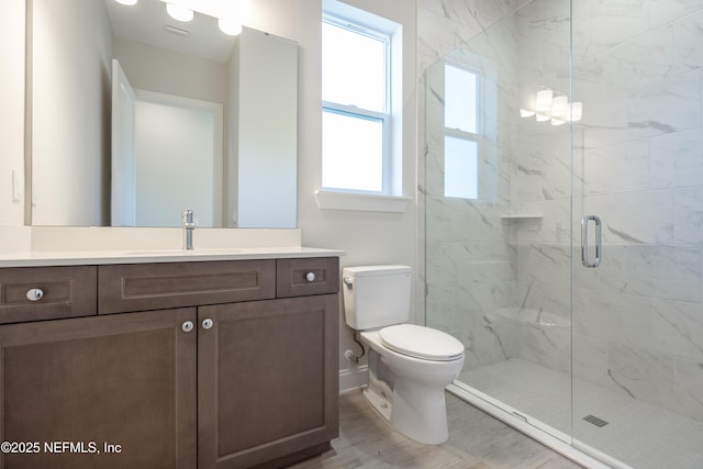 bathroom featuring vanity, toilet, and a shower with shower door