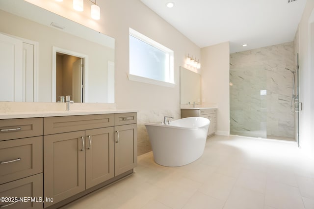 bathroom with a marble finish shower, a sink, a freestanding bath, two vanities, and recessed lighting