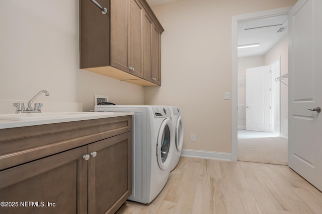 washroom featuring light hardwood / wood-style floors, cabinets, sink, and washing machine and clothes dryer