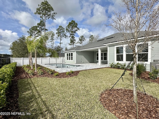 back of house featuring a lawn, a patio, a fenced backyard, roof with shingles, and a pool