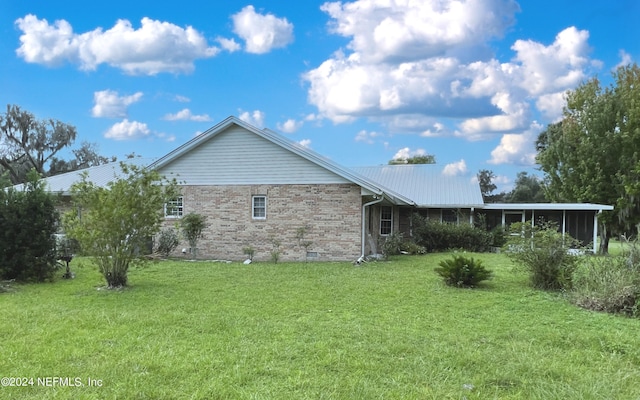 view of side of property featuring a sunroom and a lawn