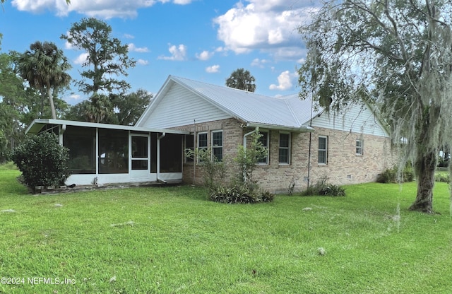 rear view of property featuring a yard and a sunroom