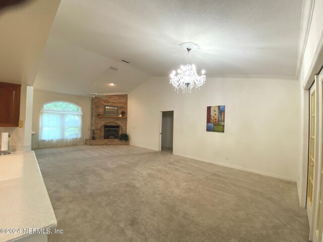 unfurnished living room featuring light carpet, high vaulted ceiling, crown molding, a fireplace, and a chandelier