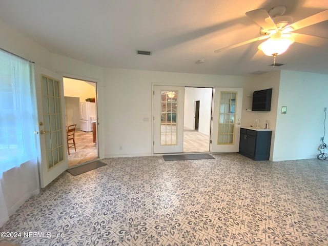 unfurnished living room with ceiling fan, french doors, and sink