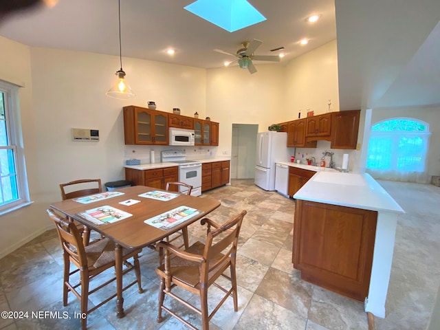 dining area featuring a skylight, ceiling fan, and a high ceiling