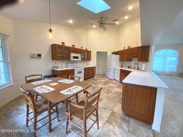 dining room featuring a wealth of natural light, a skylight, ceiling fan, and a towering ceiling