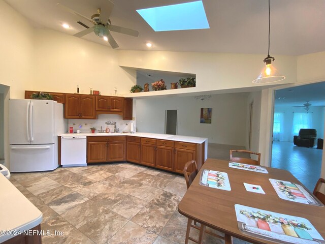 kitchen featuring white appliances, sink, hanging light fixtures, vaulted ceiling with skylight, and ceiling fan