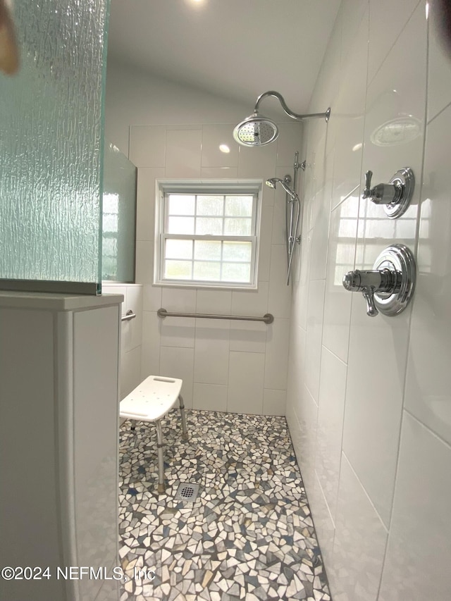 full bathroom featuring vaulted ceiling and tiled shower