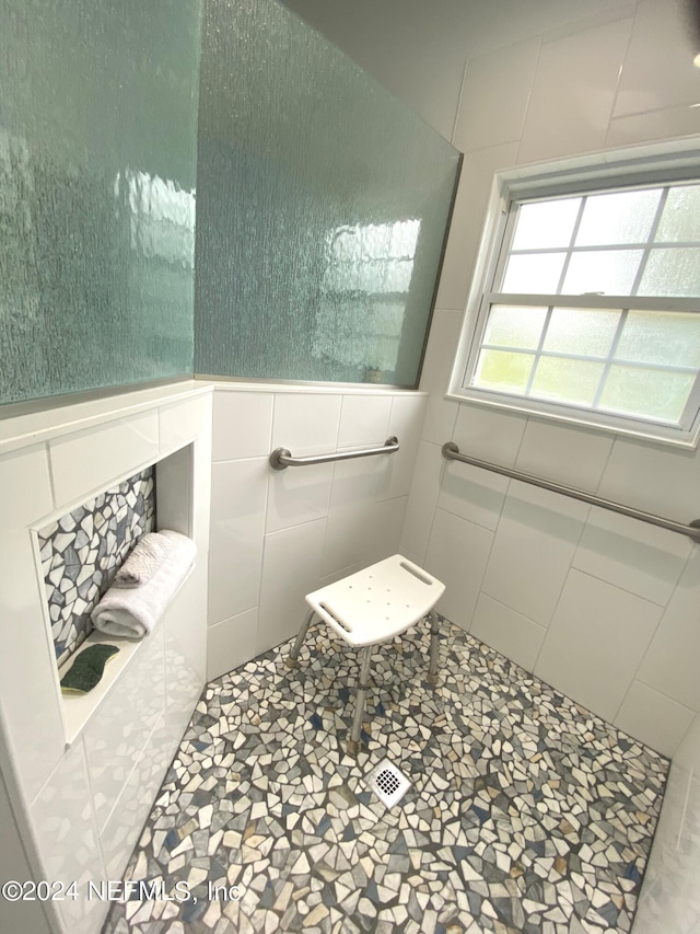 bathroom with tiled shower, wainscoting, and tile walls