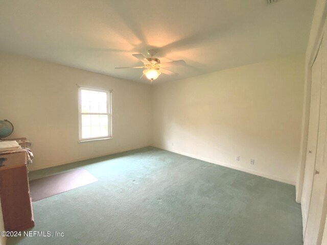 unfurnished bedroom with dark colored carpet and ceiling fan