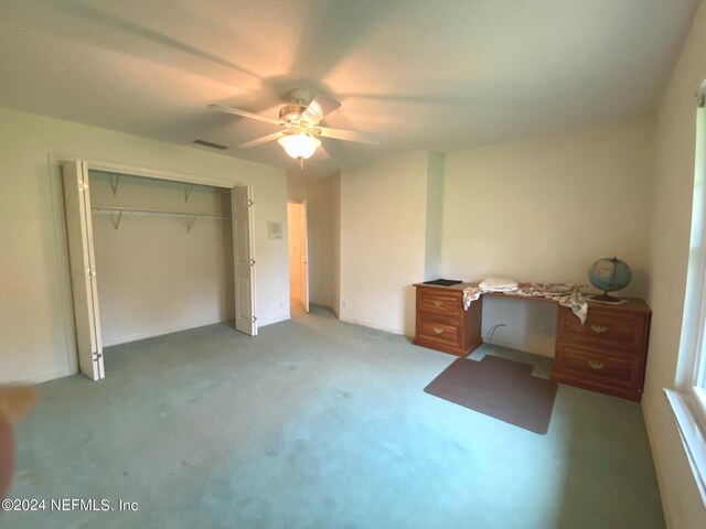 bedroom with carpet flooring, ceiling fan, built in desk, and a closet