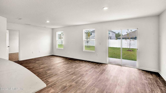 empty room with dark hardwood / wood-style floors and a textured ceiling