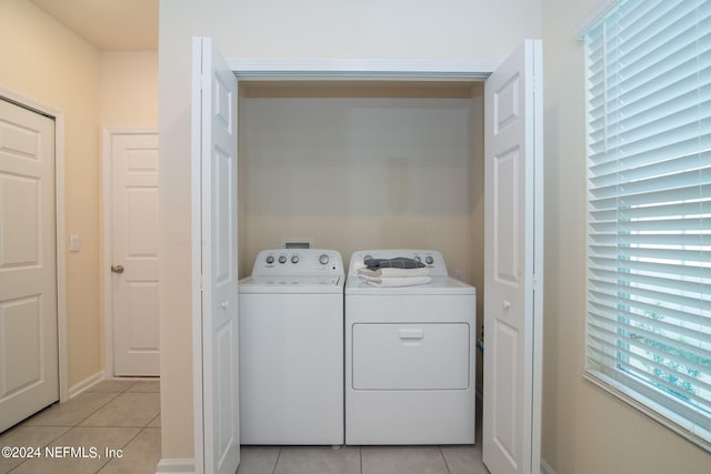 laundry area with washer and clothes dryer and light tile patterned floors