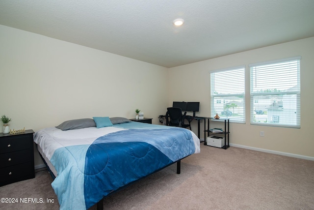 bedroom with light colored carpet and a textured ceiling