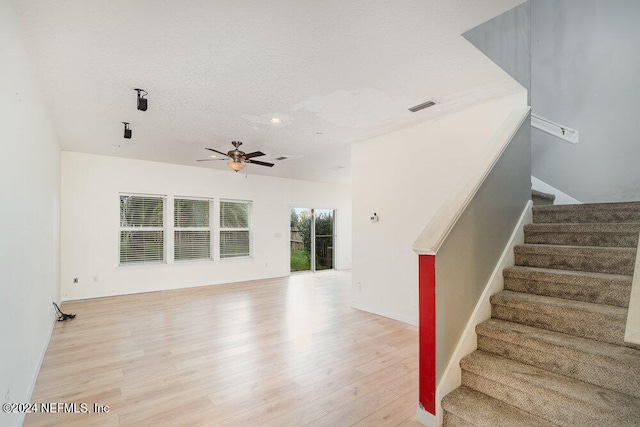 interior space with ceiling fan, wood-type flooring, and a textured ceiling