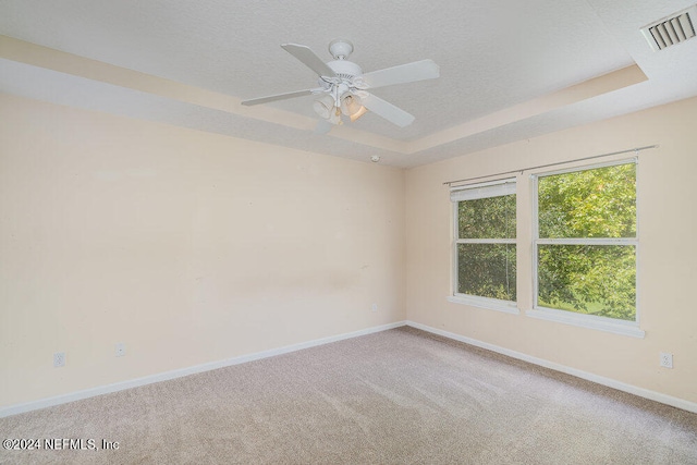 spare room featuring ceiling fan, a tray ceiling, and carpet flooring