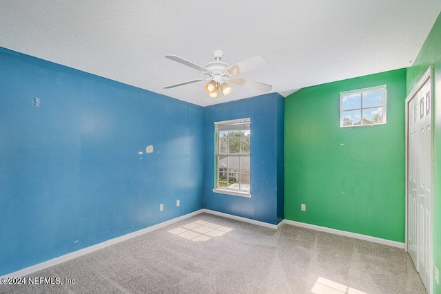 spare room featuring light carpet, a textured ceiling, and ceiling fan