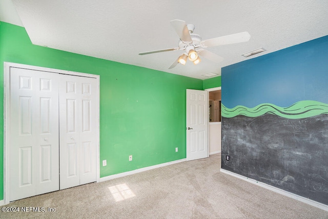 unfurnished bedroom with a closet, light carpet, a textured ceiling, and ceiling fan