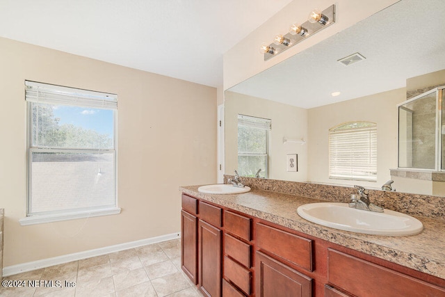 bathroom with vanity, a shower with shower door, tile patterned flooring, and a wealth of natural light