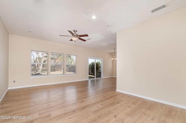 unfurnished room with ceiling fan with notable chandelier, light wood-style flooring, visible vents, and baseboards