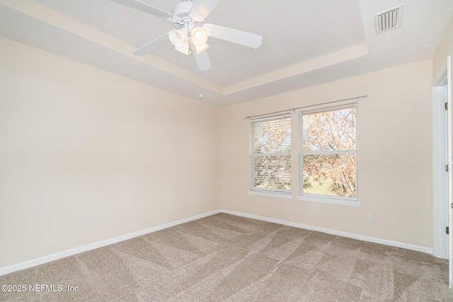 unfurnished room with carpet floors, visible vents, and a raised ceiling