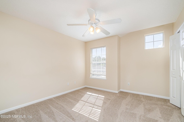 spare room with light carpet, baseboards, and a ceiling fan