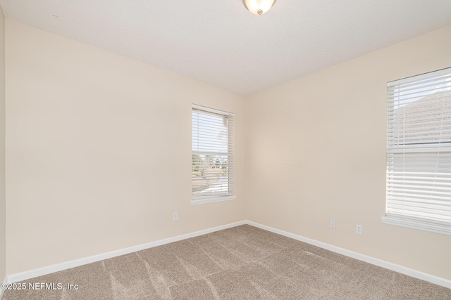 unfurnished room with light carpet, baseboards, and a textured ceiling