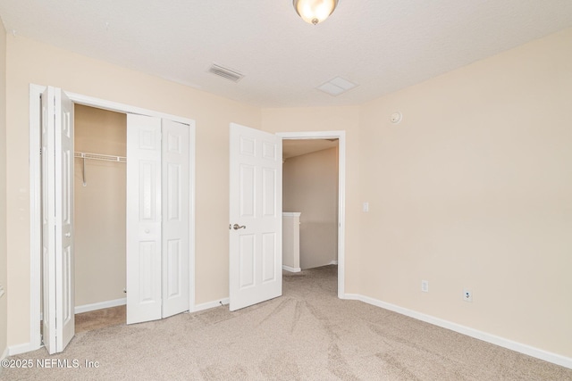 unfurnished bedroom featuring a textured ceiling, visible vents, baseboards, a closet, and carpet