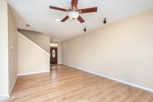 unfurnished living room with stairs, ceiling fan, visible vents, and light wood-style floors