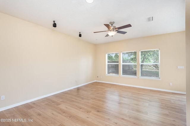 empty room featuring baseboards, light wood-type flooring, visible vents, and a ceiling fan