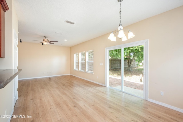 interior space featuring ceiling fan with notable chandelier, visible vents, baseboards, and light wood-style floors