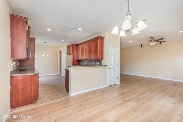 kitchen featuring ceiling fan with notable chandelier, decorative light fixtures, backsplash, and open floor plan
