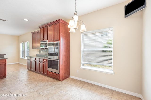 kitchen featuring an inviting chandelier, hanging light fixtures, light tile patterned floors, appliances with stainless steel finishes, and baseboards