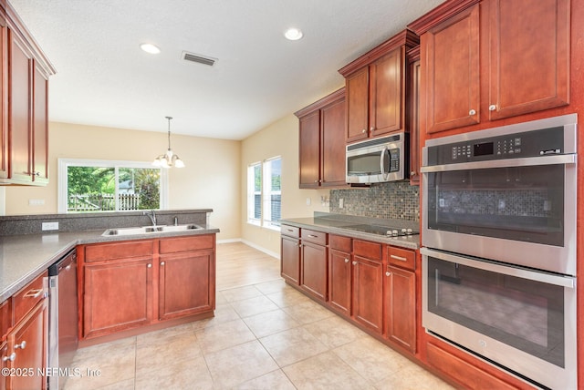 kitchen featuring a wealth of natural light, stainless steel appliances, a notable chandelier, and a sink