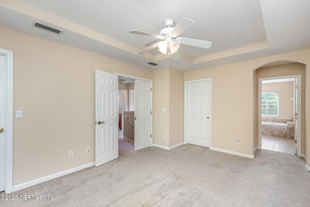 unfurnished bedroom featuring visible vents, arched walkways, a textured ceiling, and carpet flooring