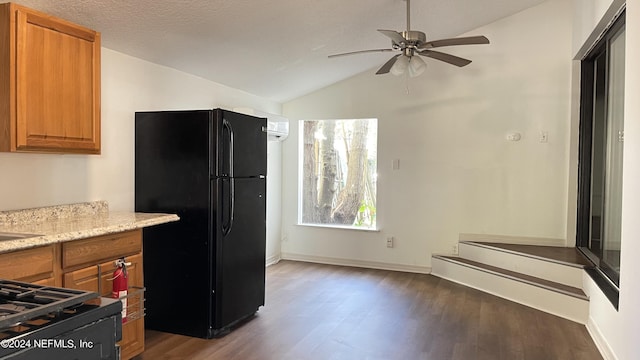 kitchen featuring lofted ceiling, freestanding refrigerator, dark wood-style floors, brown cabinetry, and gas range