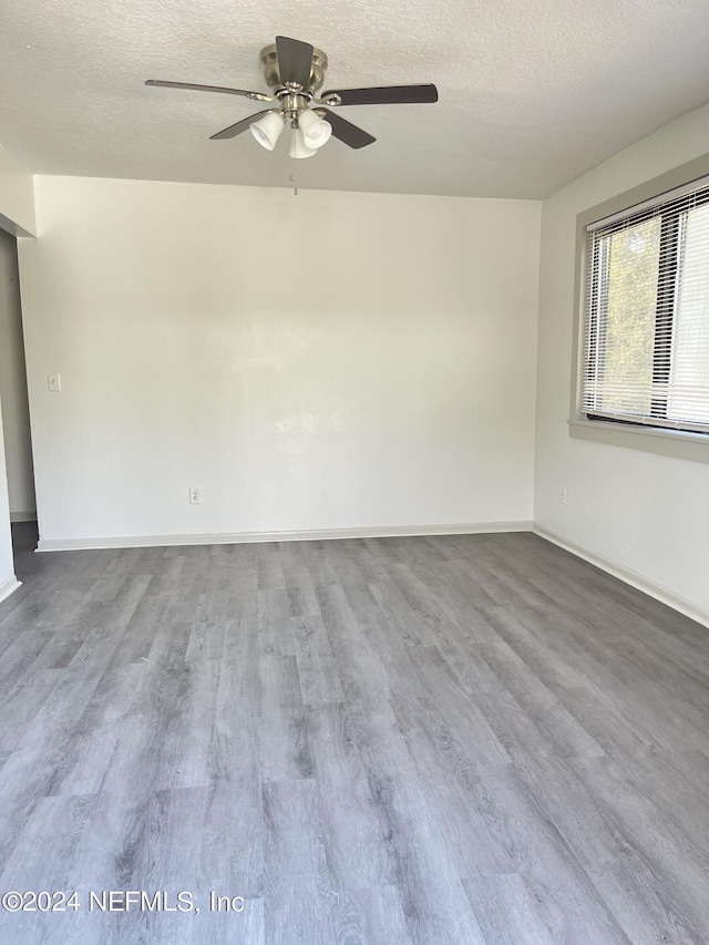 unfurnished room featuring a textured ceiling, wood finished floors, and baseboards