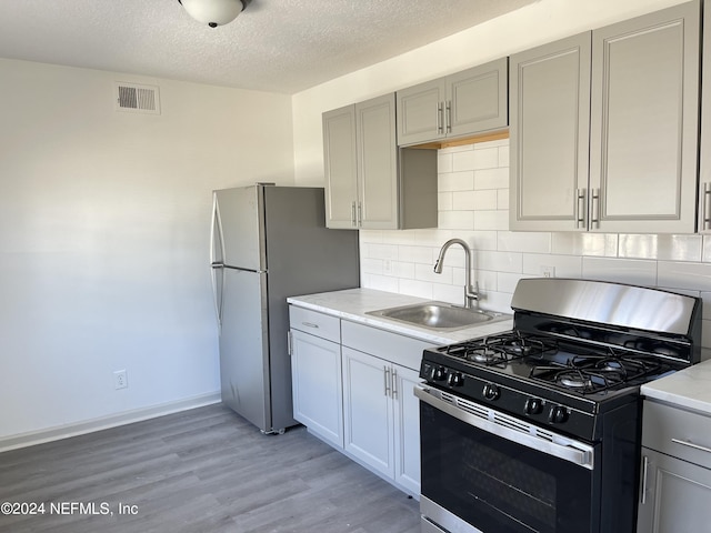 kitchen featuring tasteful backsplash, visible vents, stainless steel appliances, light countertops, and a sink