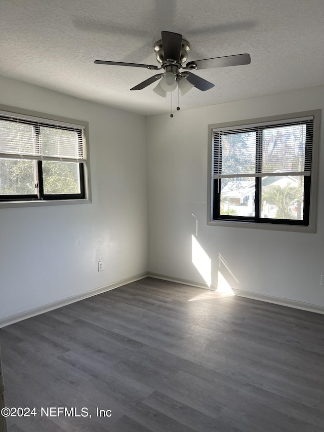 empty room featuring ceiling fan, a textured ceiling, baseboards, and dark wood-type flooring