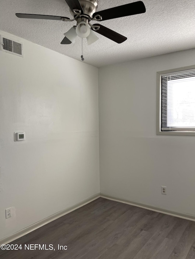 spare room with dark wood-style flooring, visible vents, a ceiling fan, a textured ceiling, and baseboards