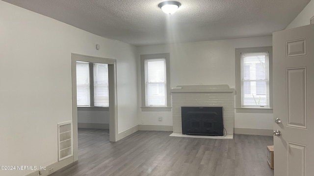 unfurnished living room with visible vents, a fireplace, baseboards, and wood finished floors