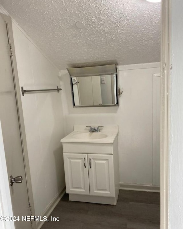 bathroom featuring a textured ceiling, vaulted ceiling, wood finished floors, and vanity