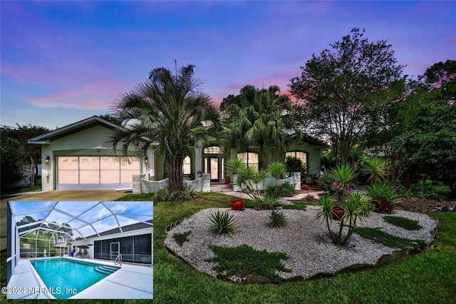 back house at dusk featuring a garage and a lanai