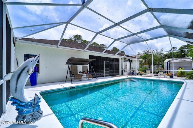 view of swimming pool featuring a water slide, a shed, glass enclosure, and a patio area